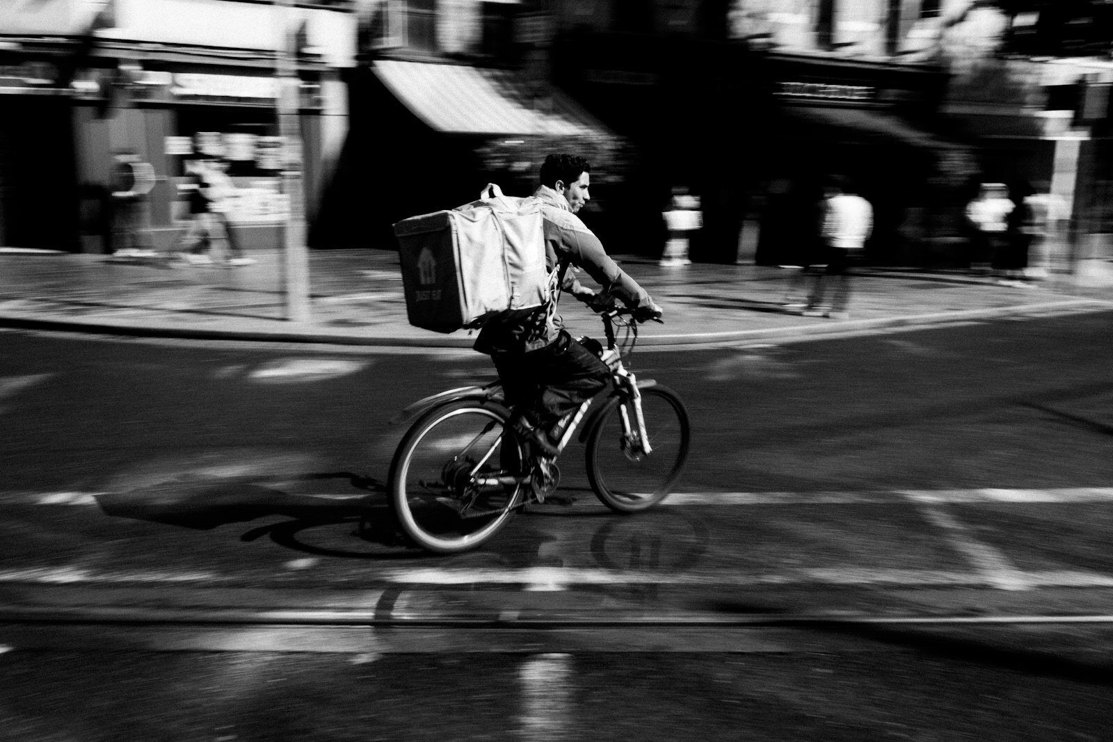 Cyclist with delivery box rides through a blurry city street.