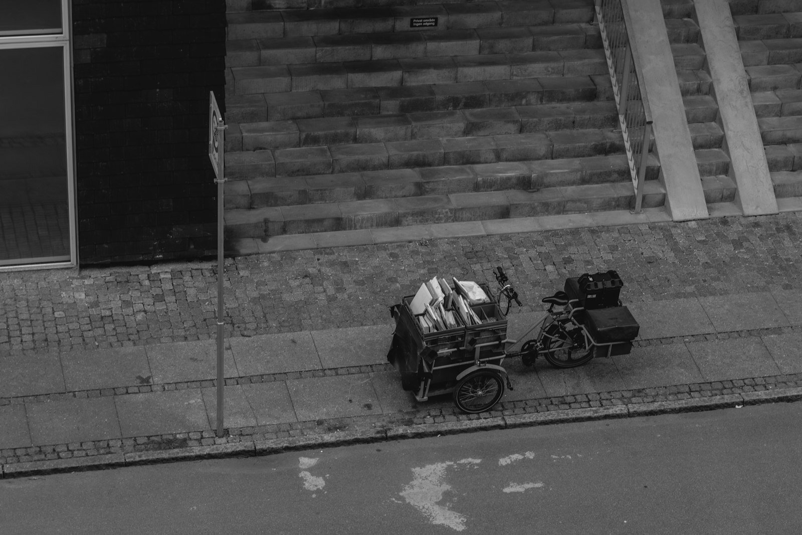 A tricycle loaded with goods parked on a sidewalk.